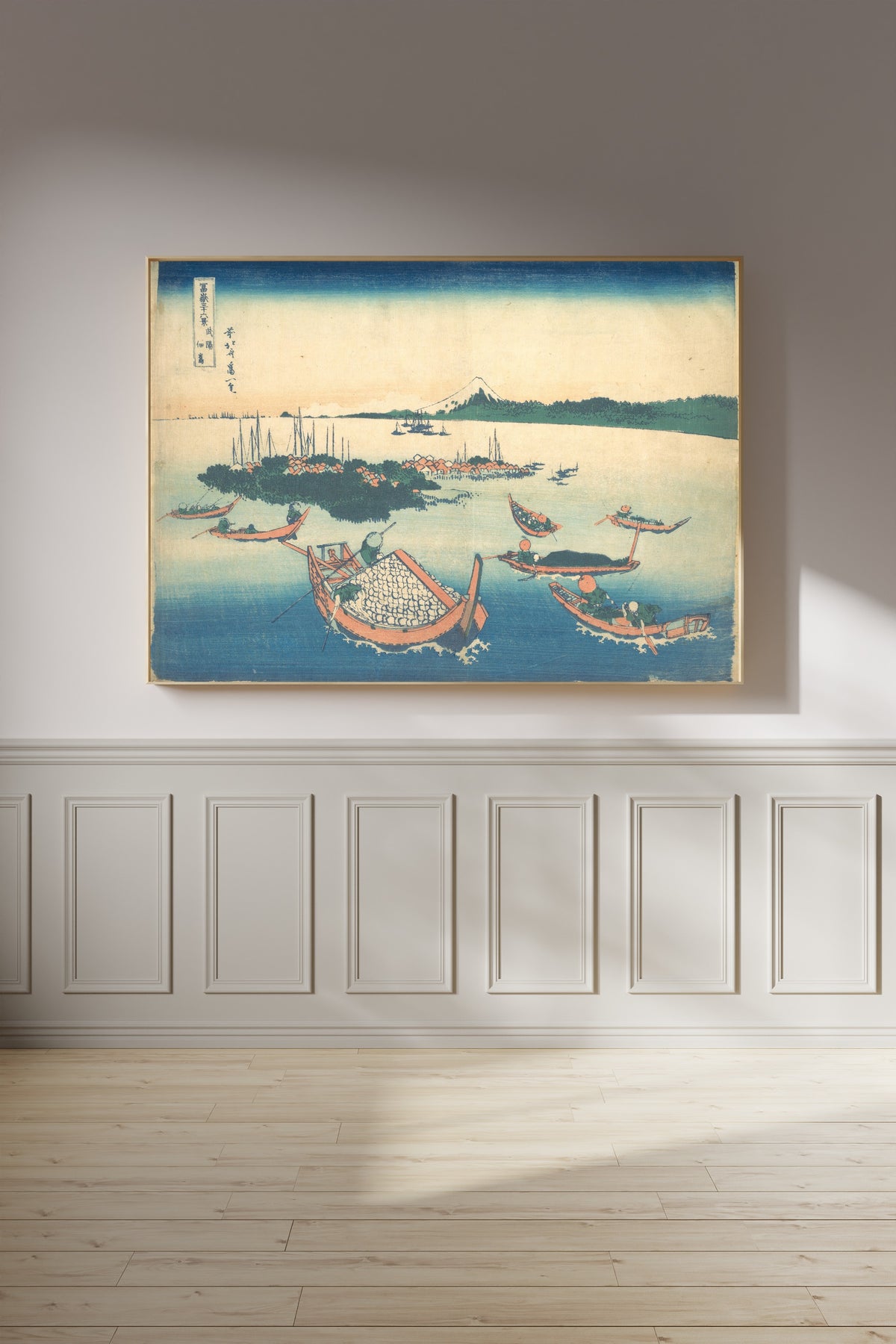 Framed art print of Thirty-six Views of Mount Fuji: Tsukudajima in Musashi Province by Katsushika Hokusai, on a panelled wall in afternoon light