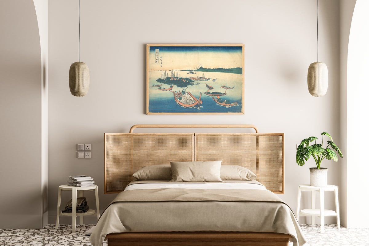Framed art print of Thirty-six Views of Mount Fuji: Tsukudajima in Musashi Province by Katsushika Hokusai, above a cane-headboard bed