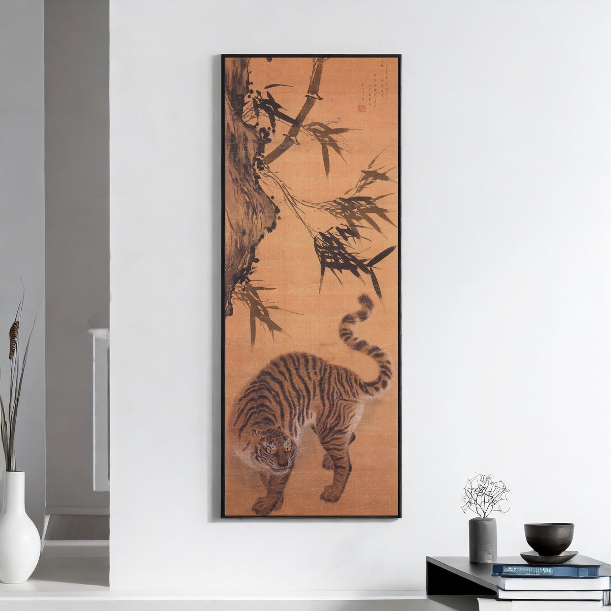 Framed art print of Tiger under Bamboo by Kim Hong-do (Danwon), on a white wall above books and a bowl