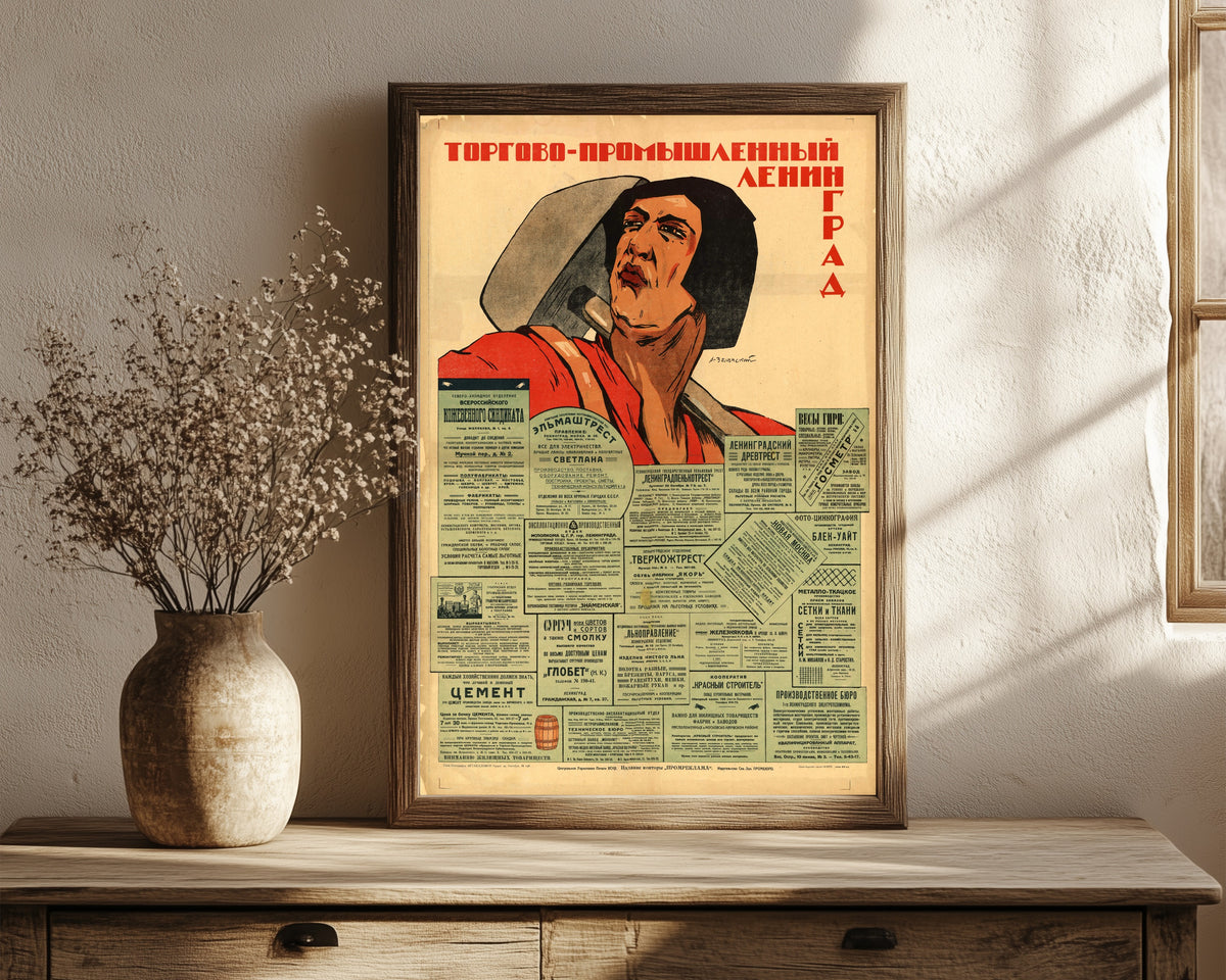 Framed art print of Trade and Industrial Leningrad by Alexander Zelensky, in a dark wood frame leaning on a rustic console beside dried flowers