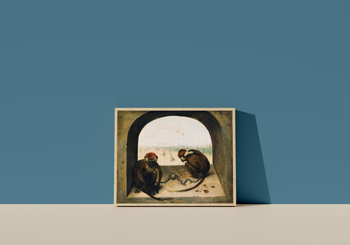 Framed art print of Two Chained Monkeys by Pieter Bruegel the Elder, in a light wood frame leaning on a blue wall