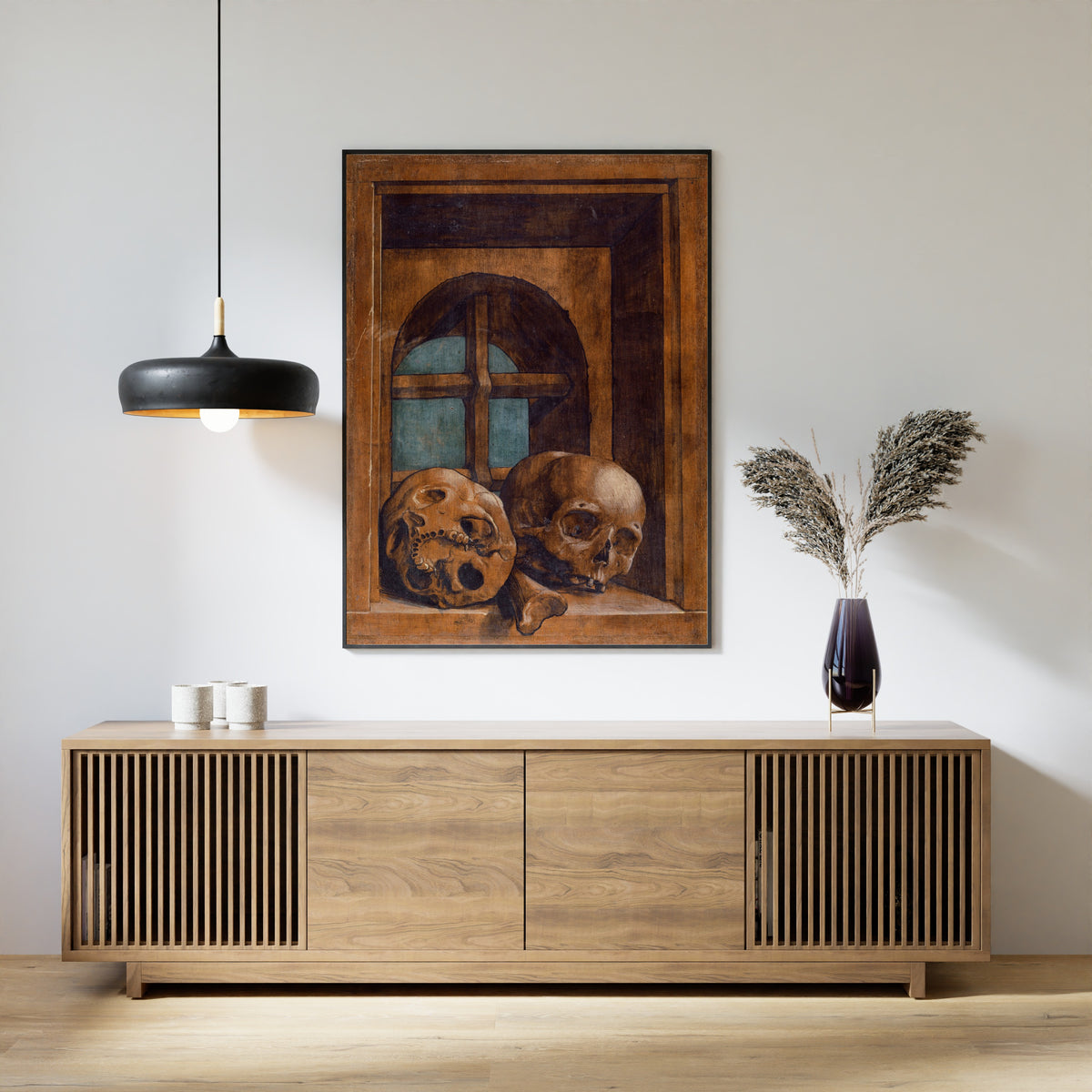 Framed art print of Two Skulls in a Window Niche by Hans Holbein the Younger, above a slatted wood sideboard