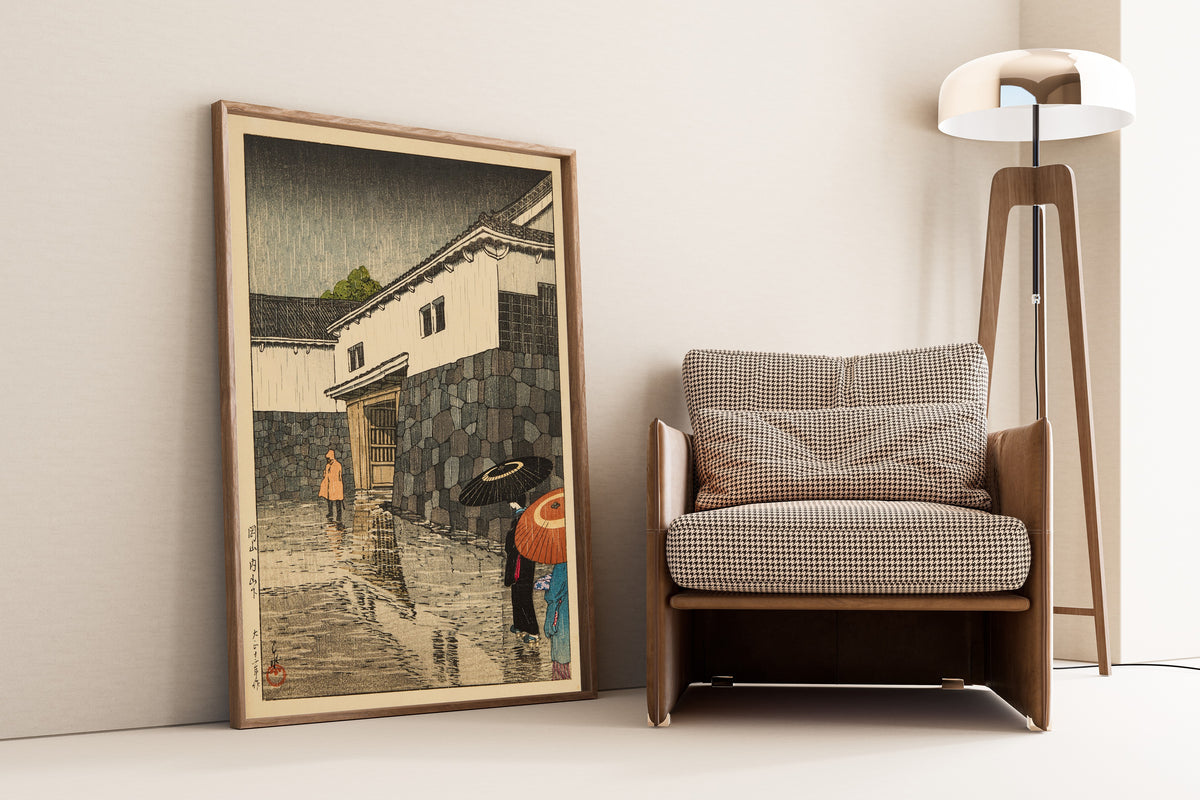 Framed art print of Uchiyamashita, Okayama by Kawase Hasui, leaning against a wall beside an armchair and a floor lamp