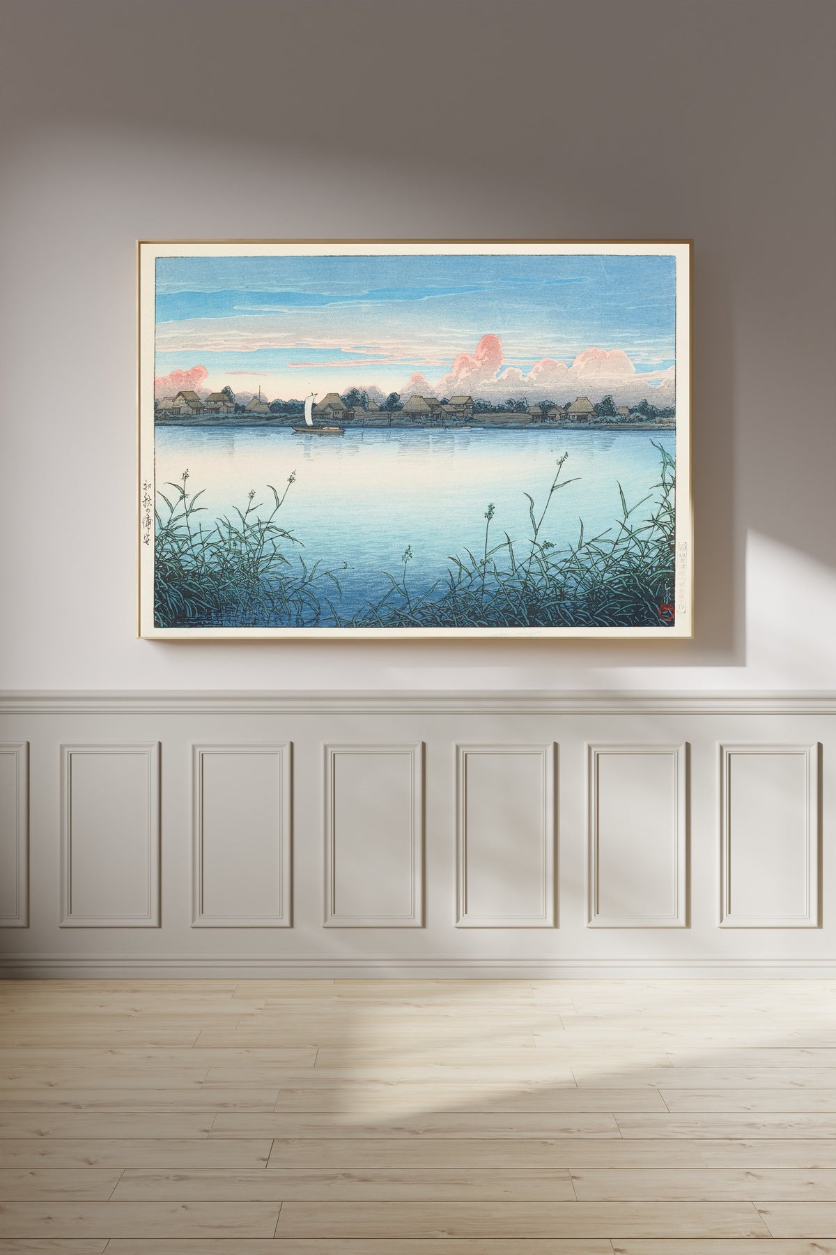 Framed art print of Urayasu in Early Autumn by Kawase Hasui, on a panelled wall in afternoon light