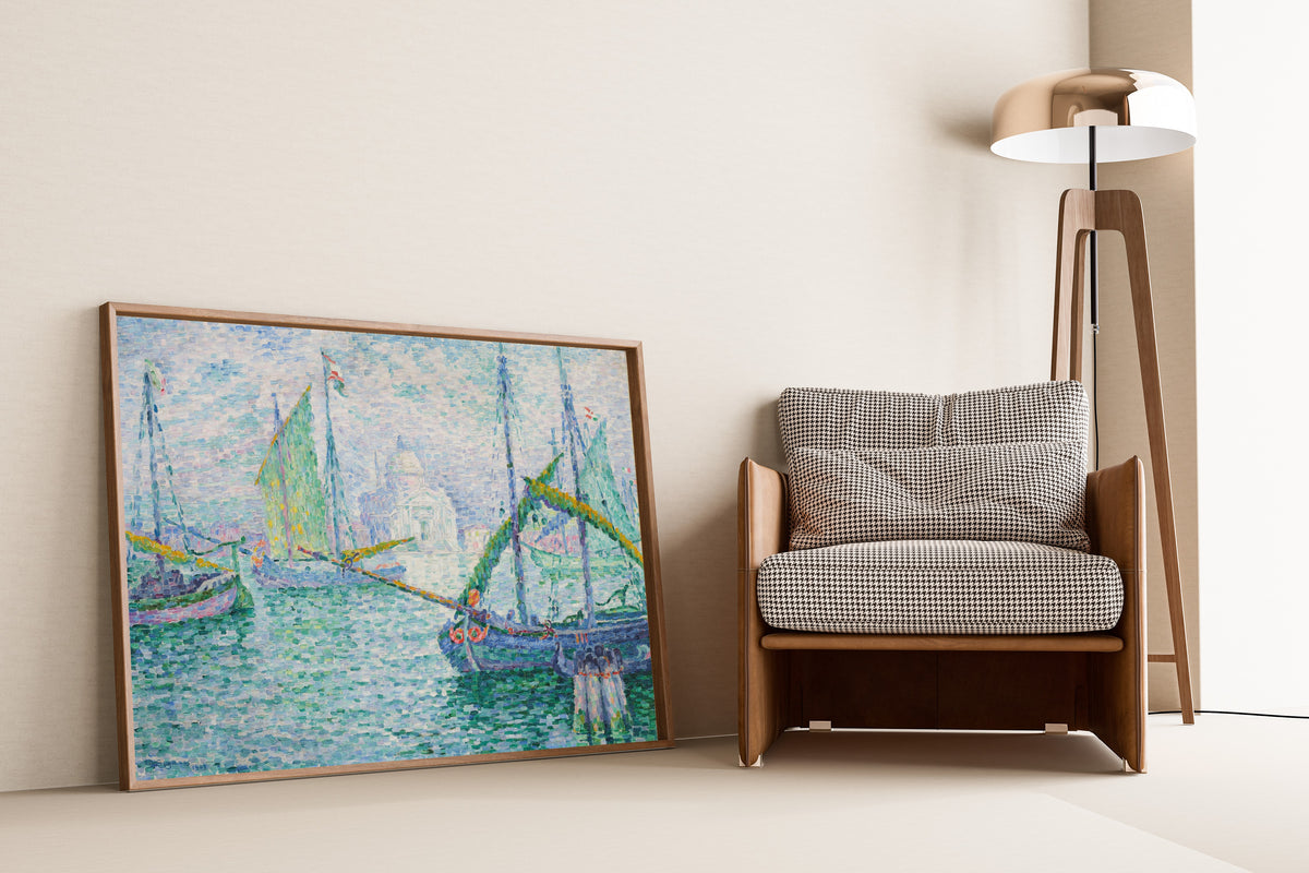 Framed art print of Venice, Il Redentore by Paul Signac, leaning against a wall beside an armchair and a floor lamp