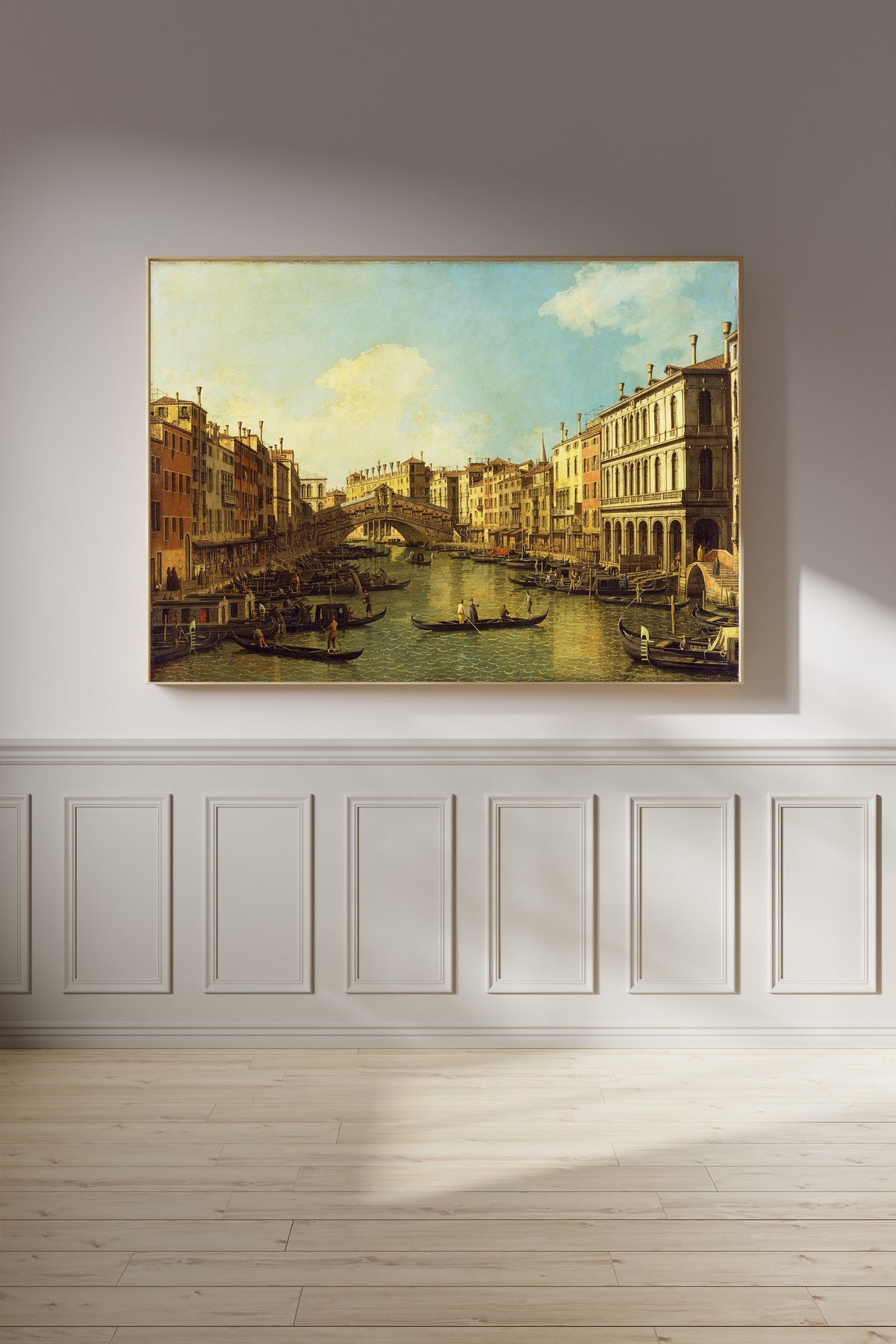 Framed art print of Venice, the Grand Canal from the Palazzo Dolfin-Manin to the Rialto Bridge by Canaletto, on a panelled wall in afternoon light