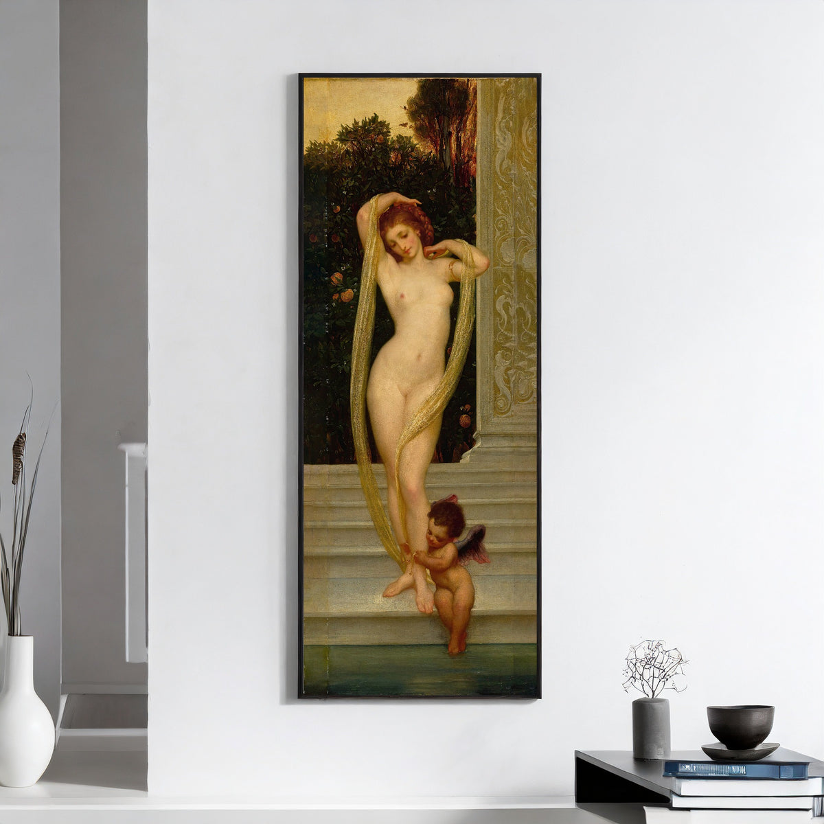 Framed art print of Venus and Cupid by Frederic Leighton, on a white wall above books and a bowl