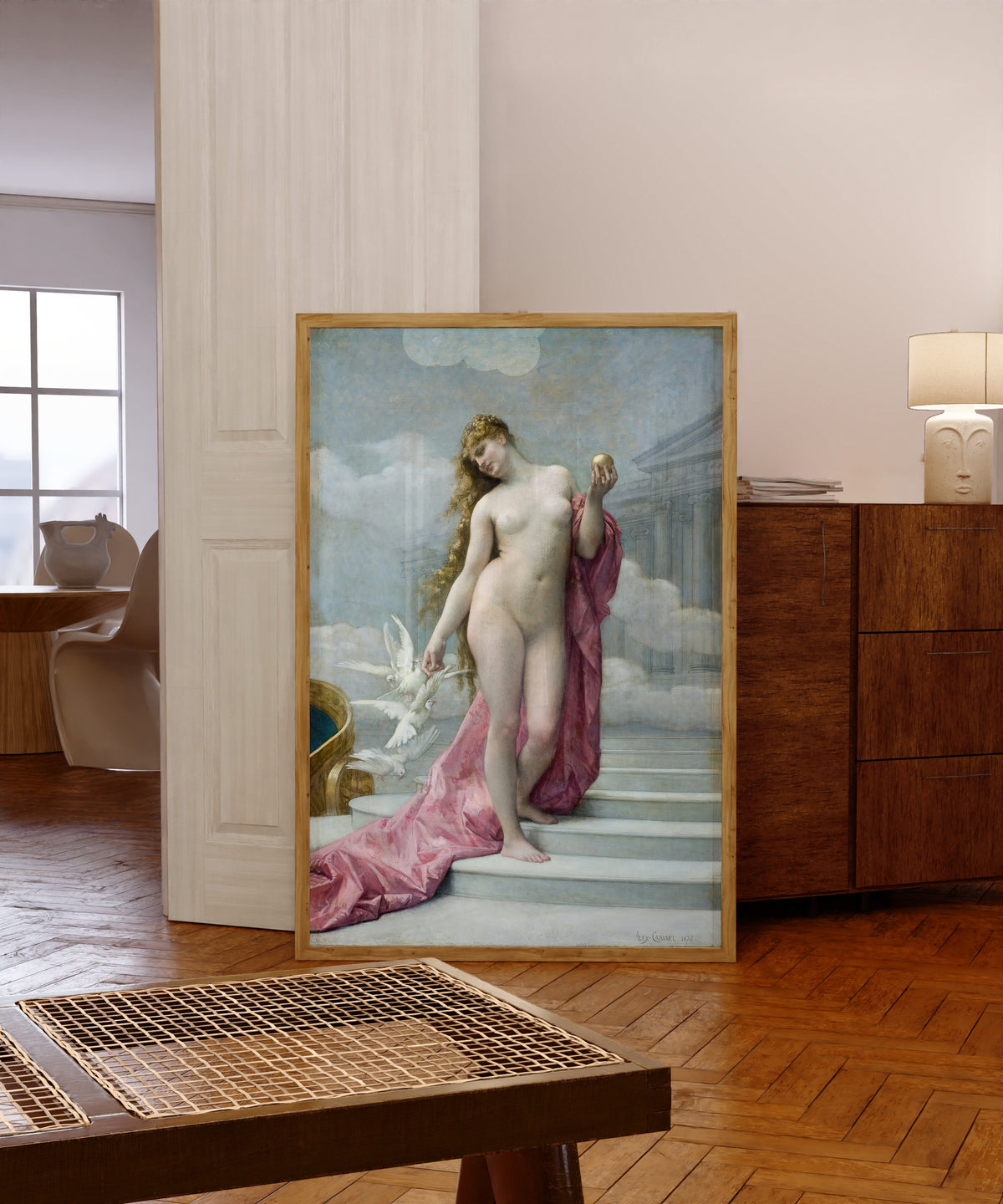 Framed art print of Venus by Alexandre Cabanel, in a light wood frame leaning in a warm room with a parquet floor