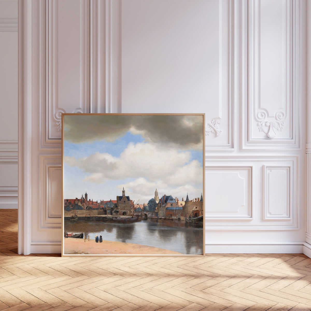 Framed art print of View of Delft by Johannes Vermeer, leaning against pale pink panelling on a herringbone floor