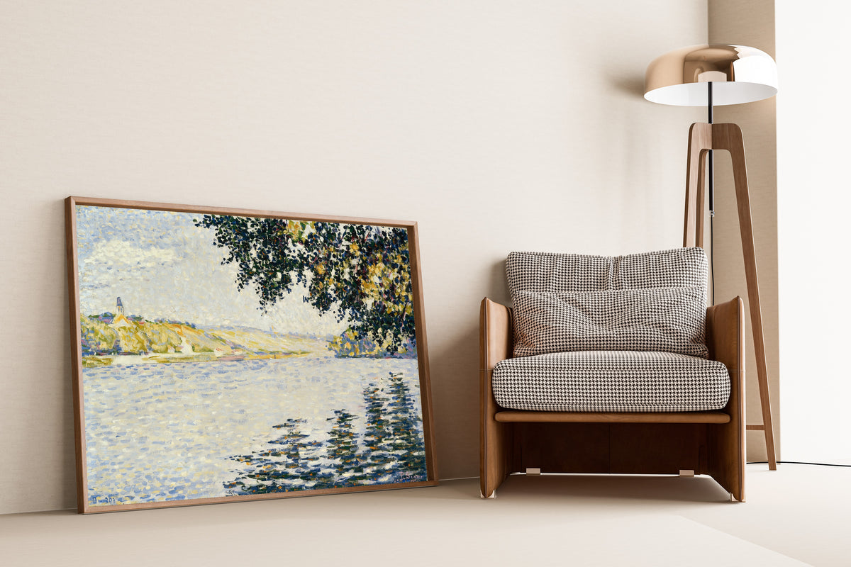 Framed art print of View of the Seine at Herblay by Paul Signac, leaning against a wall beside an armchair and a floor lamp