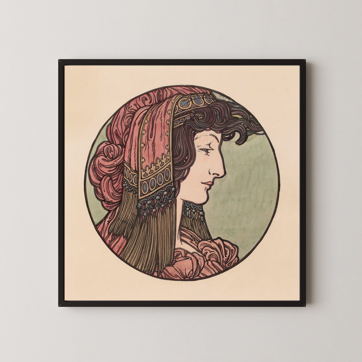 Framed art print of Vitrail pour la façade de la boutique Fouquet (pink headcloth) by Alphonse Mucha, in a black frame on a pale wall