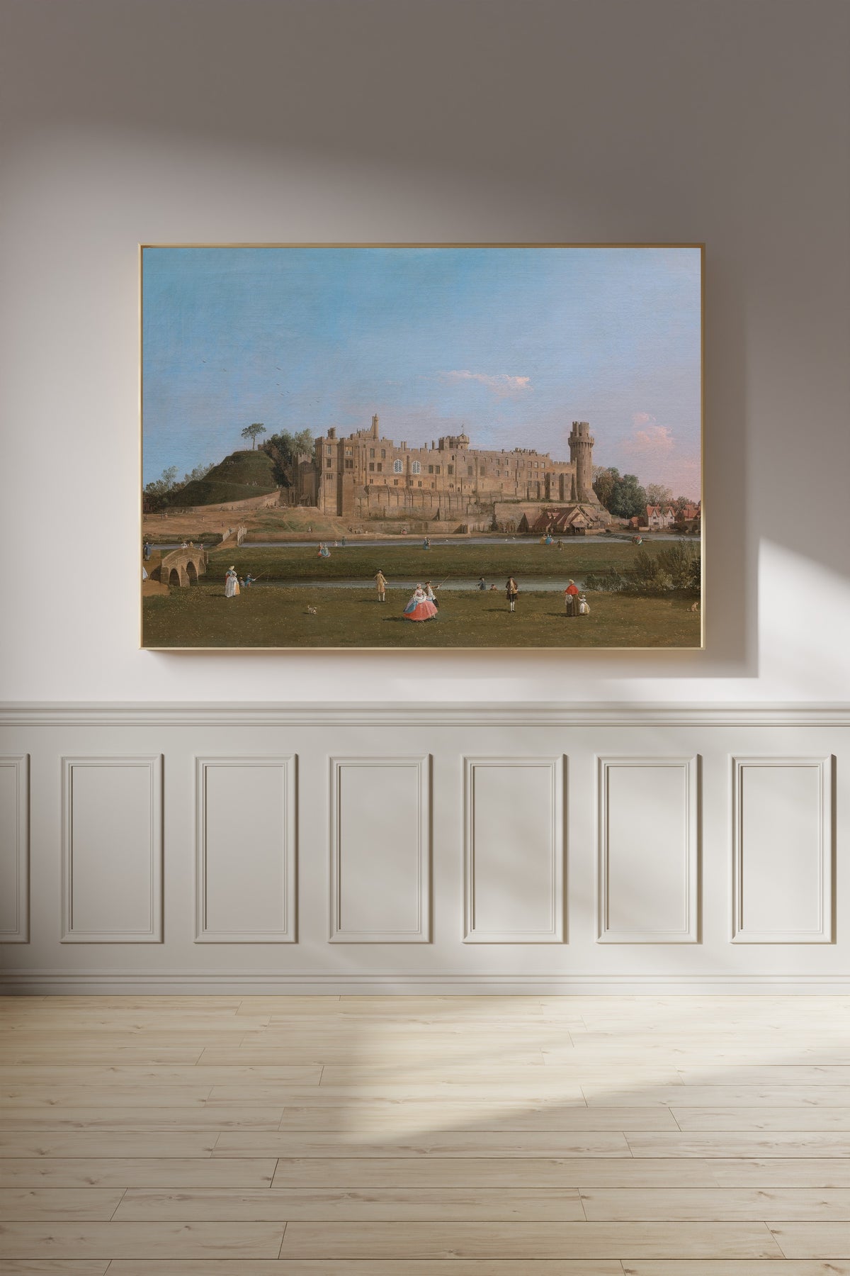 Framed art print of Warwick Castle by Canaletto, on a panelled wall in afternoon light