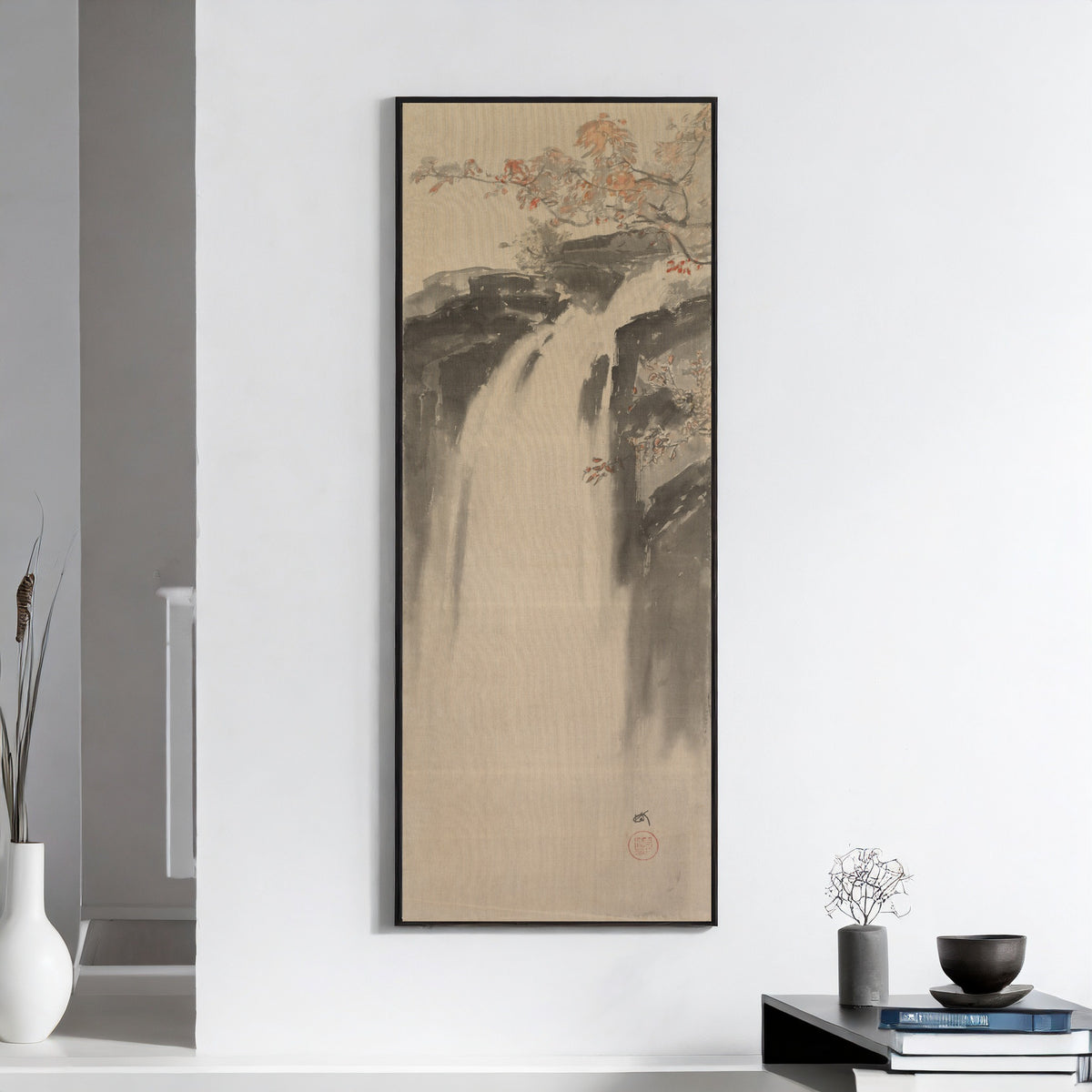 Framed art print of Waterfall by Hiroshi Yoshida, on a white wall above books and a bowl