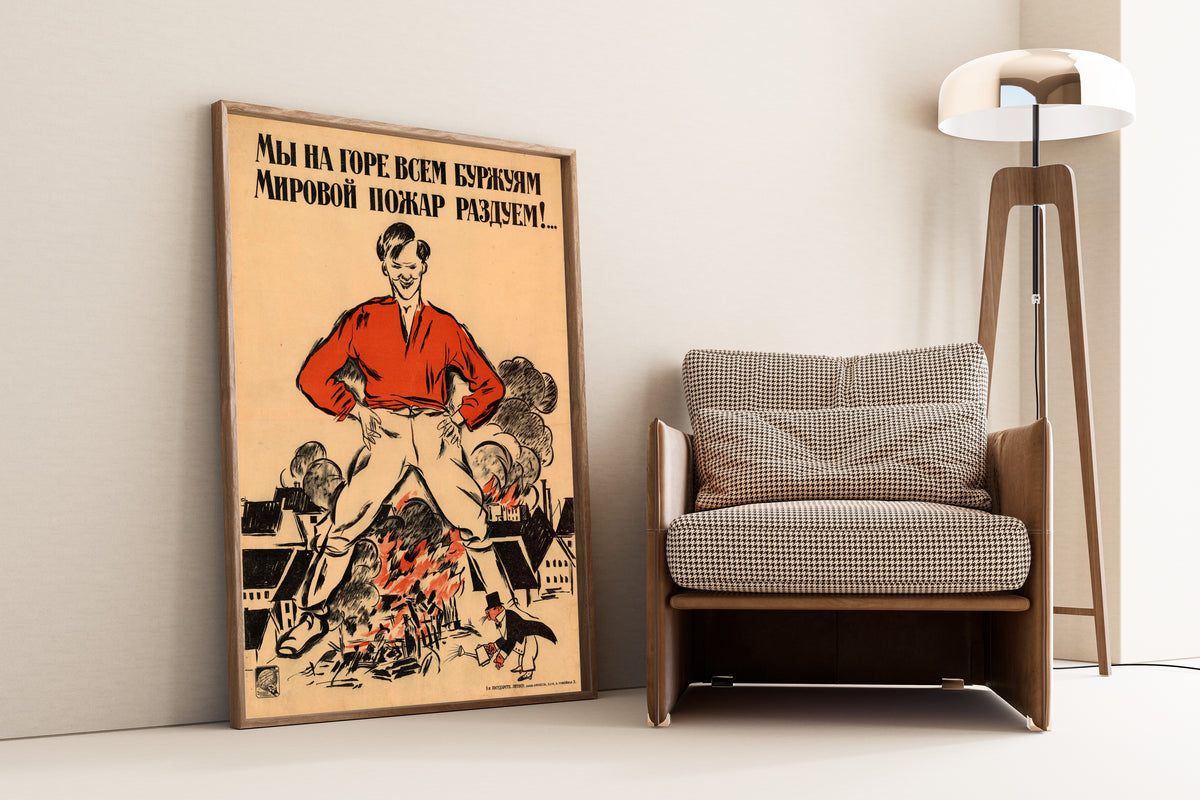 Framed art print of We Will Fan a World Fire to the Grief of All Bourgeois by Alexander Zelensky, leaning against a wall beside an armchair and a floor lamp