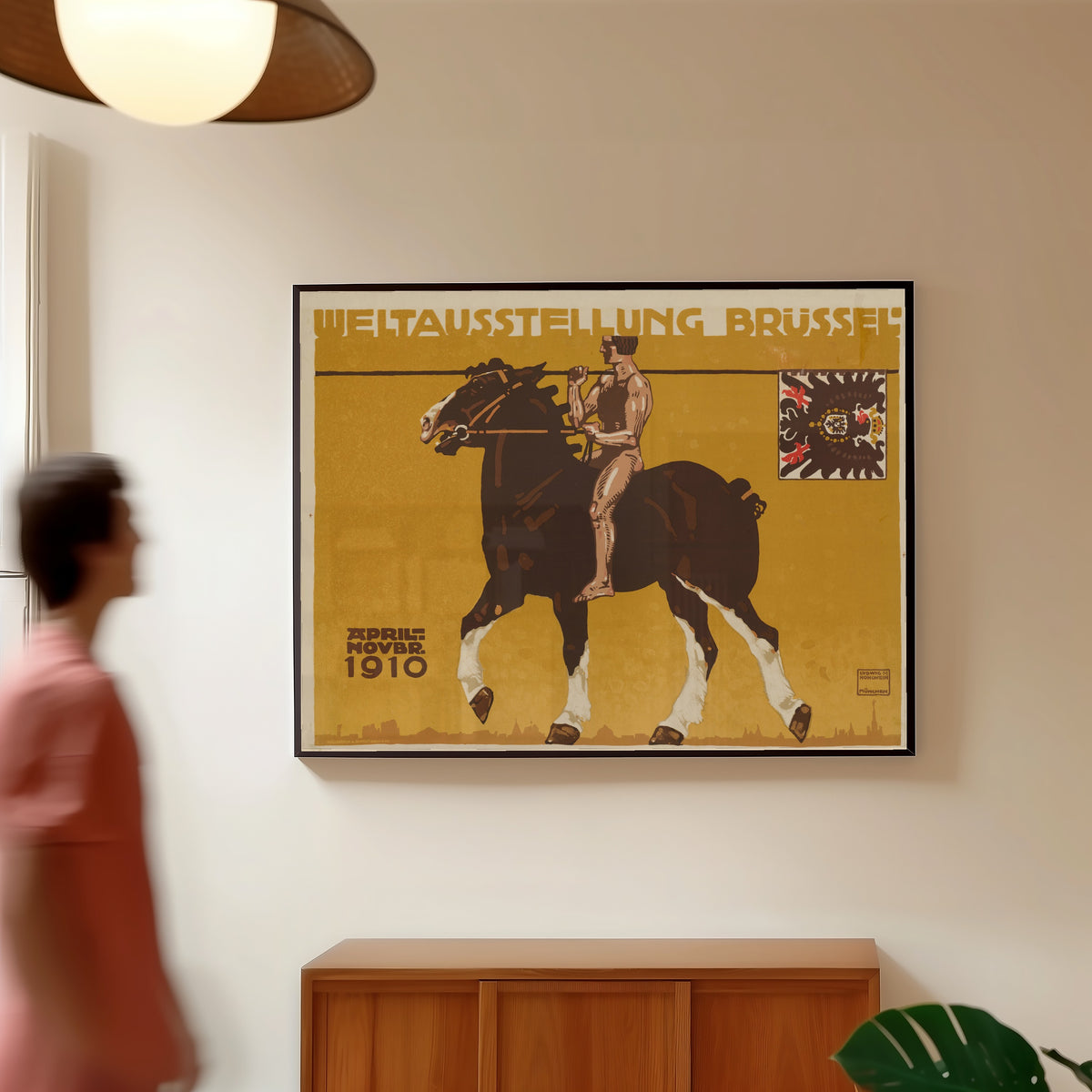 Framed art print of Weltausstellung Brüssel 1910 by Ludwig Hohlwein, in a slim black frame on a warm wall in a sunlit room