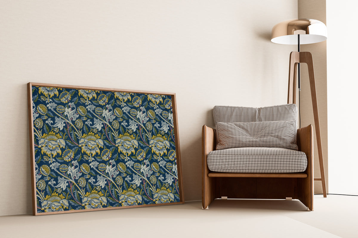 Framed art print of Wey (Blue) by William Morris, leaning against a wall beside an armchair and a floor lamp