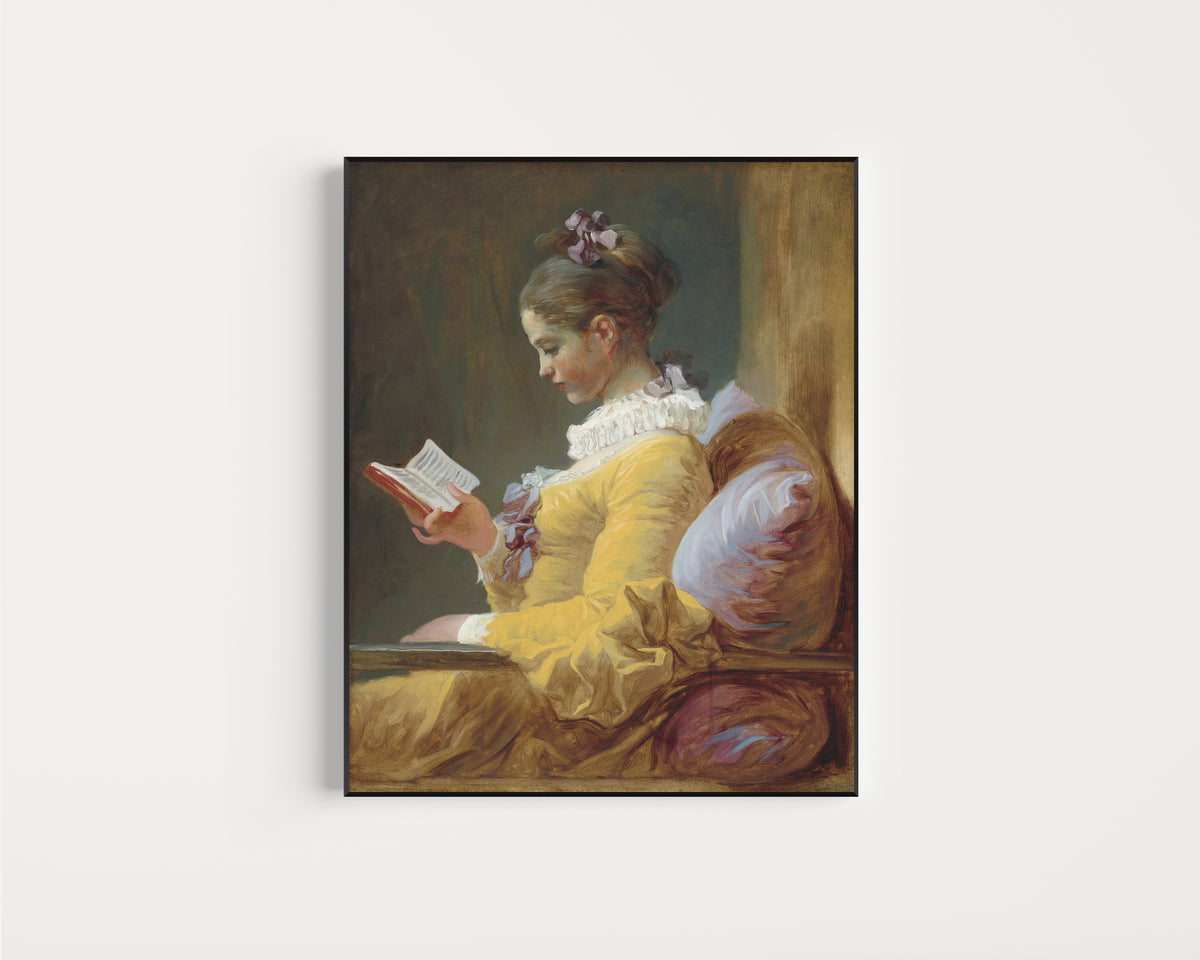 Framed art print of Young Girl Reading by Jean-Honoré Fragonard, in a slim black frame on a plain white wall