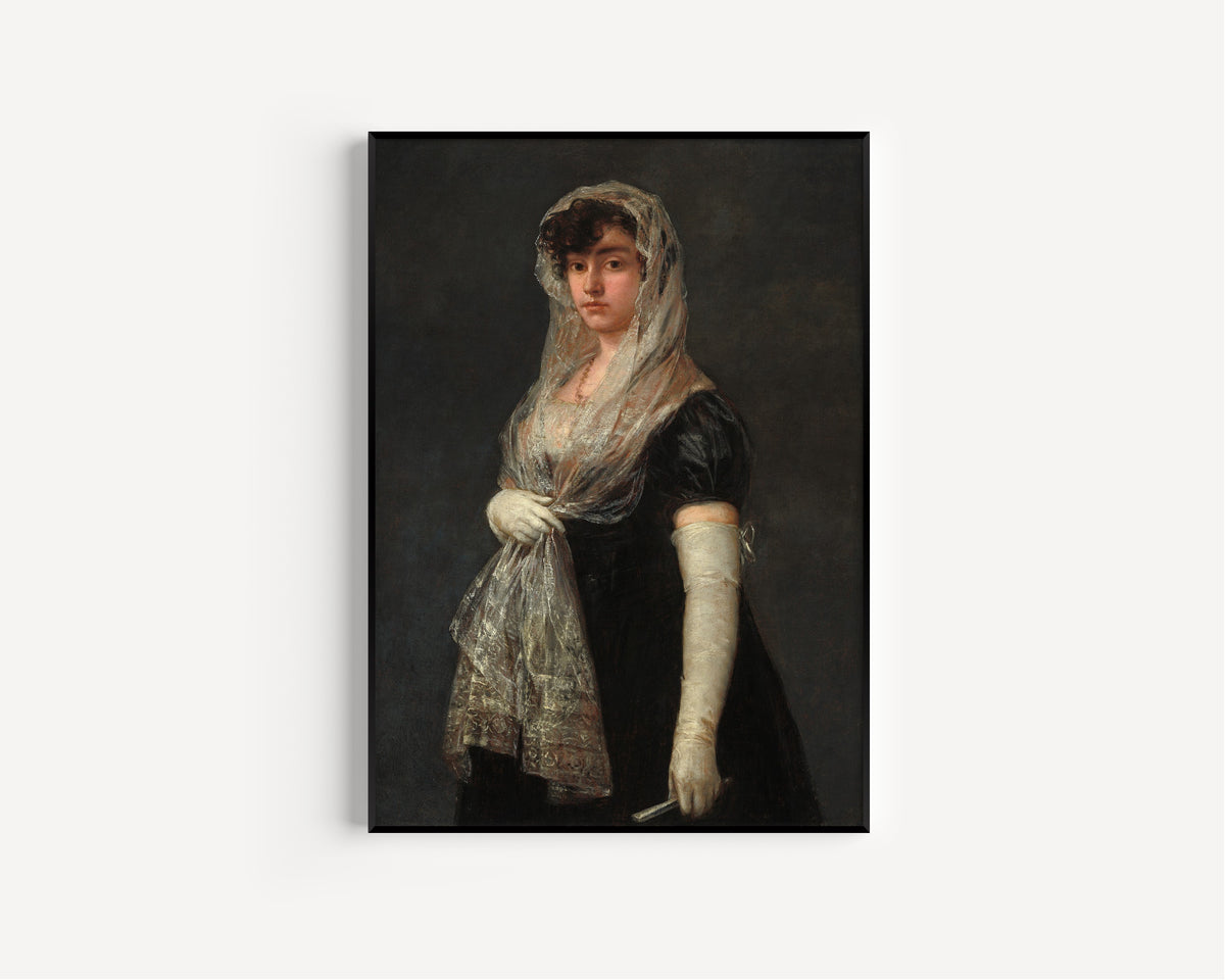 Framed art print of Young Lady Wearing a Mantilla and Basquina by Francisco de Goya, in a slim black frame on a plain white wall