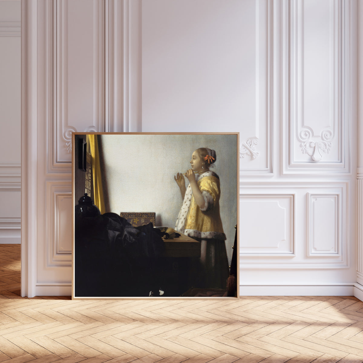 Framed art print of Young Woman with a Pearl Necklace by Johannes Vermeer, leaning against pale pink panelling on a herringbone floor