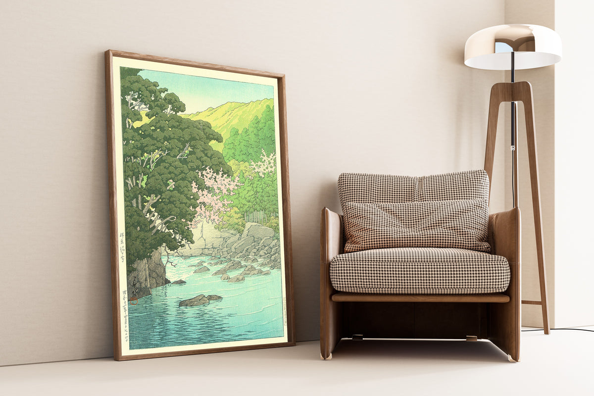 Framed art print of Yugashima, Izu by Kawase Hasui, leaning against a wall beside an armchair and a floor lamp