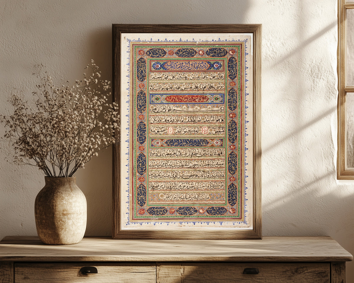 Framed art print of Page from a Manuscript of the Qur'an (end page), in a dark wood frame leaning on a rustic console beside dried flowers