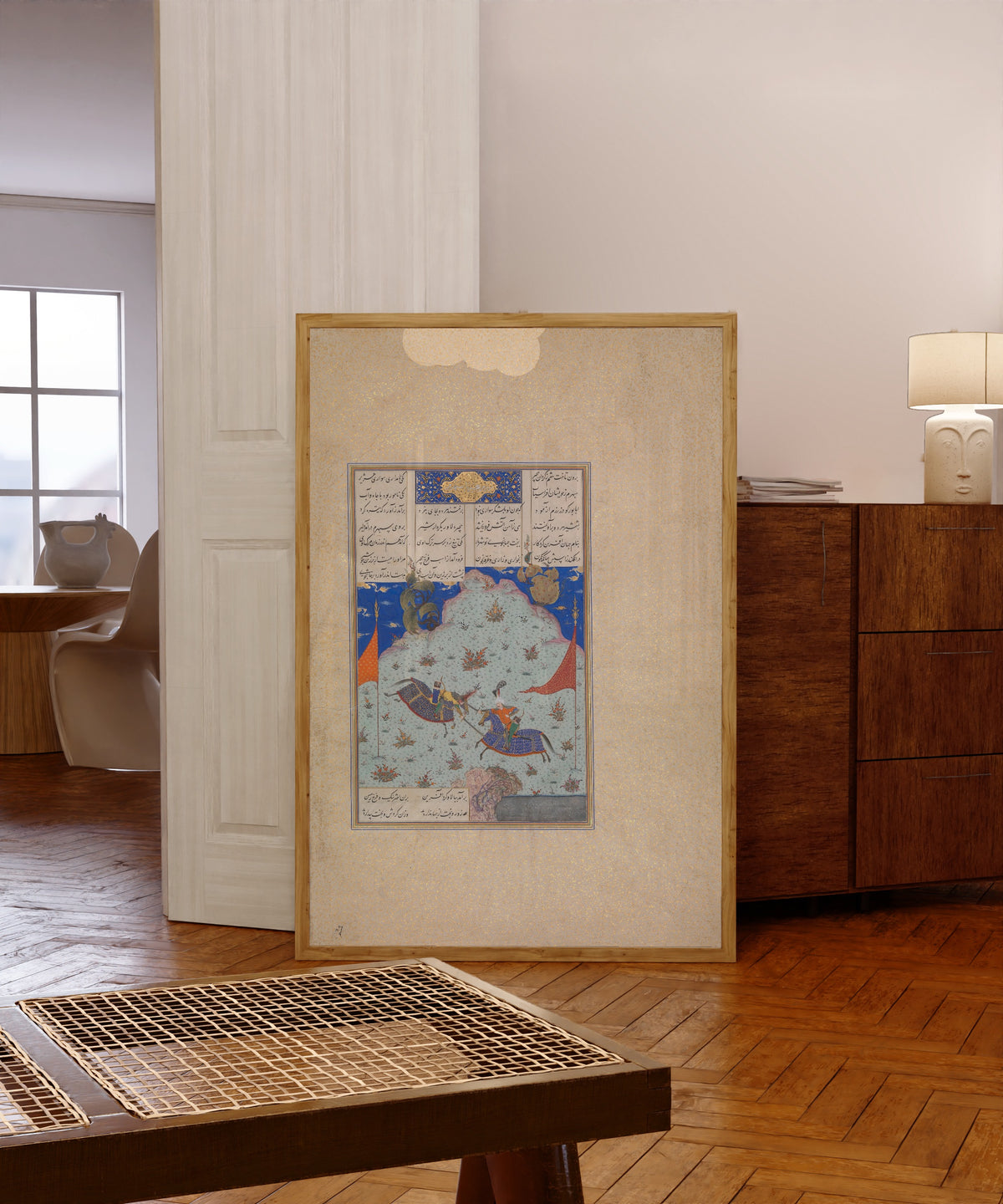Framed art print of Shahnama of Shah Tahmasp: The Sixth Joust… by Abd al-Vahhab (attributed), in a light wood frame leaning in a warm room with a parquet floor