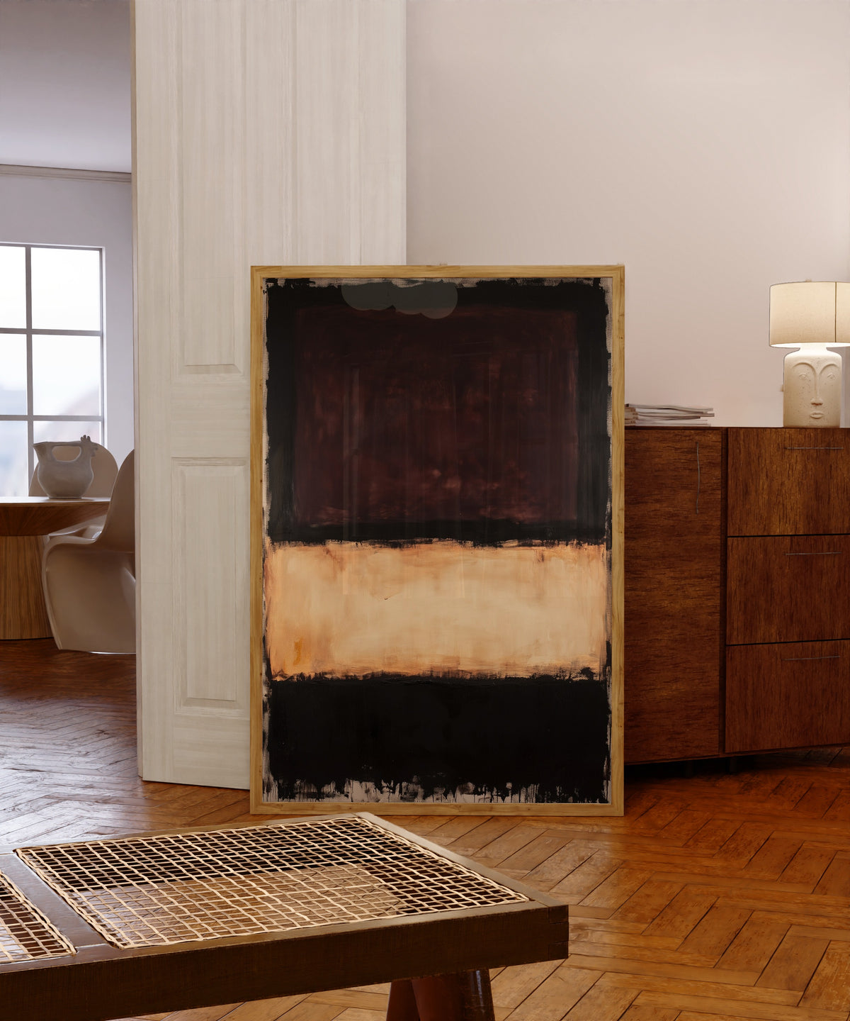 Framed art print of Colour Field: Beige, Brown, Black by After Mark Rothko, in a light wood frame leaning in a warm room with a parquet floor