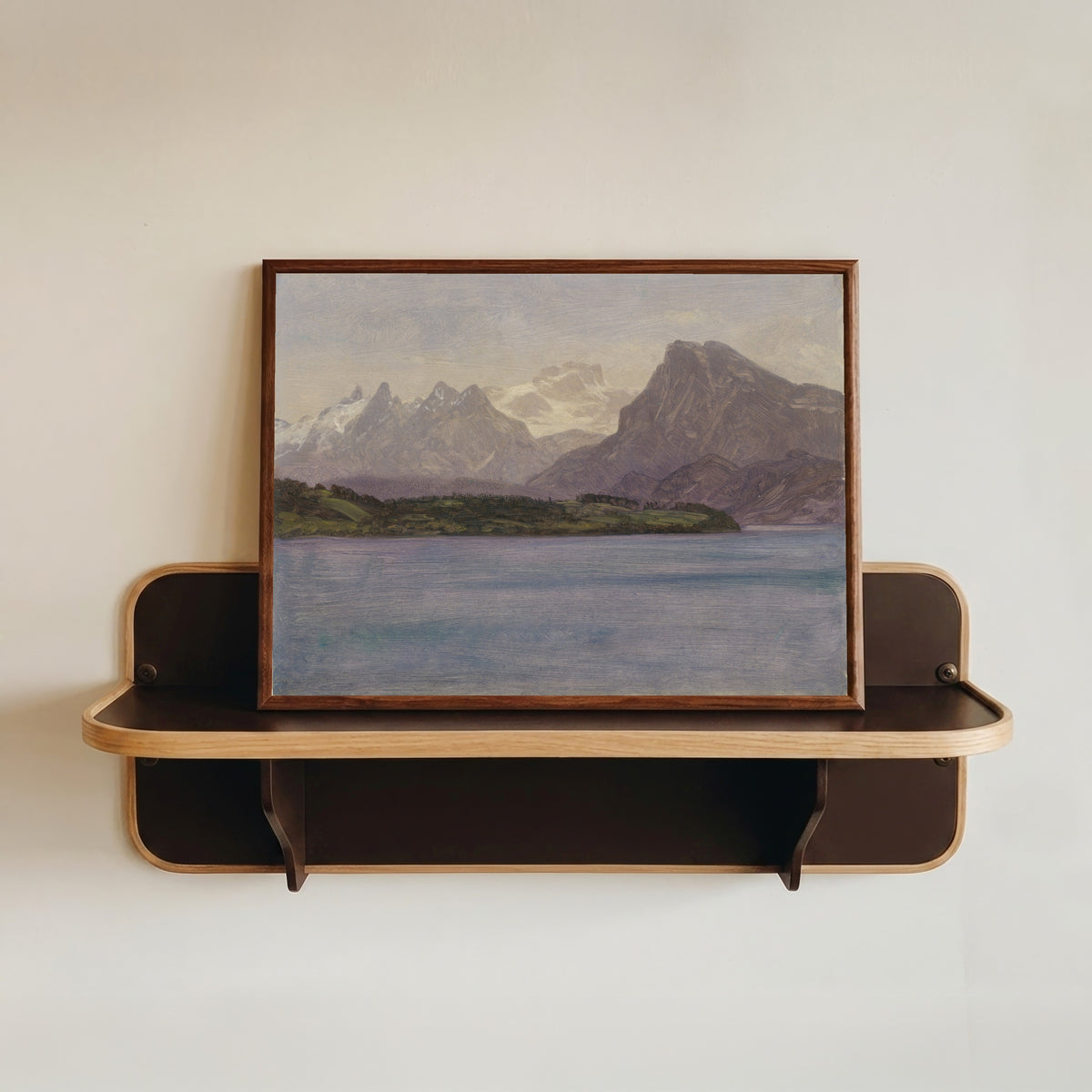 Framed art print of Alaskan Coast Range by Albert Bierstadt, in a dark wood frame resting on a wall shelf