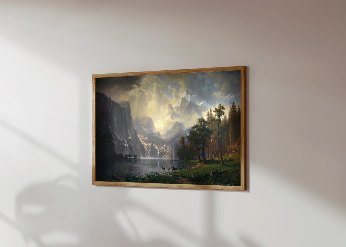Framed art print of Among the Sierra Nevada, California by Albert Bierstadt, in a light wood frame on a sunlit white wall, seen at a slight angle