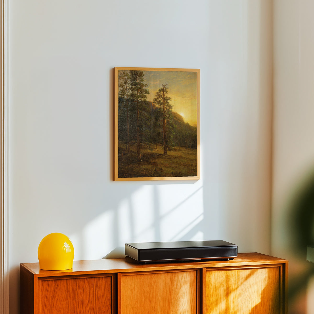 Framed art print of California Redwoods by Albert Bierstadt, in a light wood frame on a white wall above an orange sideboard