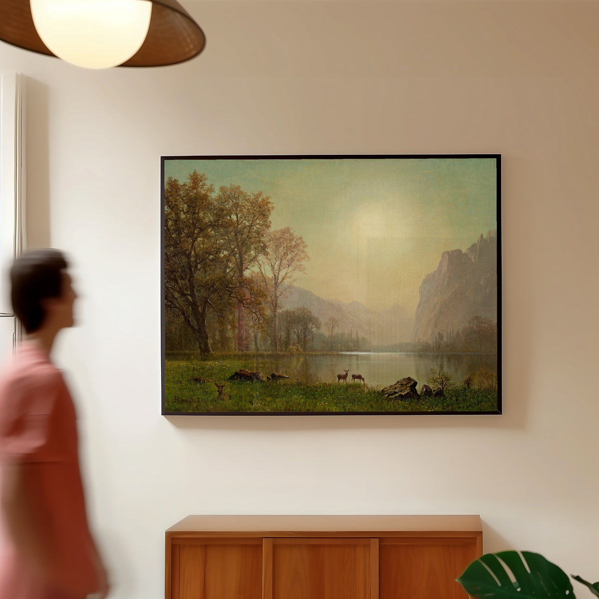 Framed art print of Dawn in the Rockies by Albert Bierstadt, in a slim black frame on a warm wall in a sunlit room