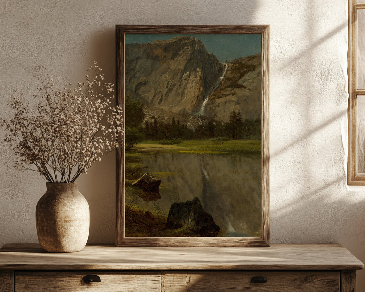 Framed art print of Hetch Hetchy Falls, California by Albert Bierstadt, in a dark wood frame leaning on a rustic console beside dried flowers