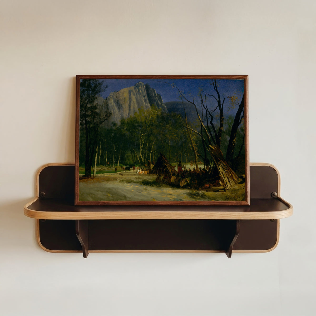 Framed art print of Indians in Council, California by Albert Bierstadt, in a dark wood frame resting on a wall shelf