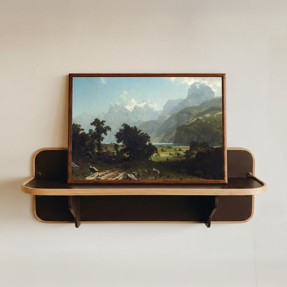 Framed art print of Lake Lucerne by Albert Bierstadt, in a dark wood frame resting on a wall shelf