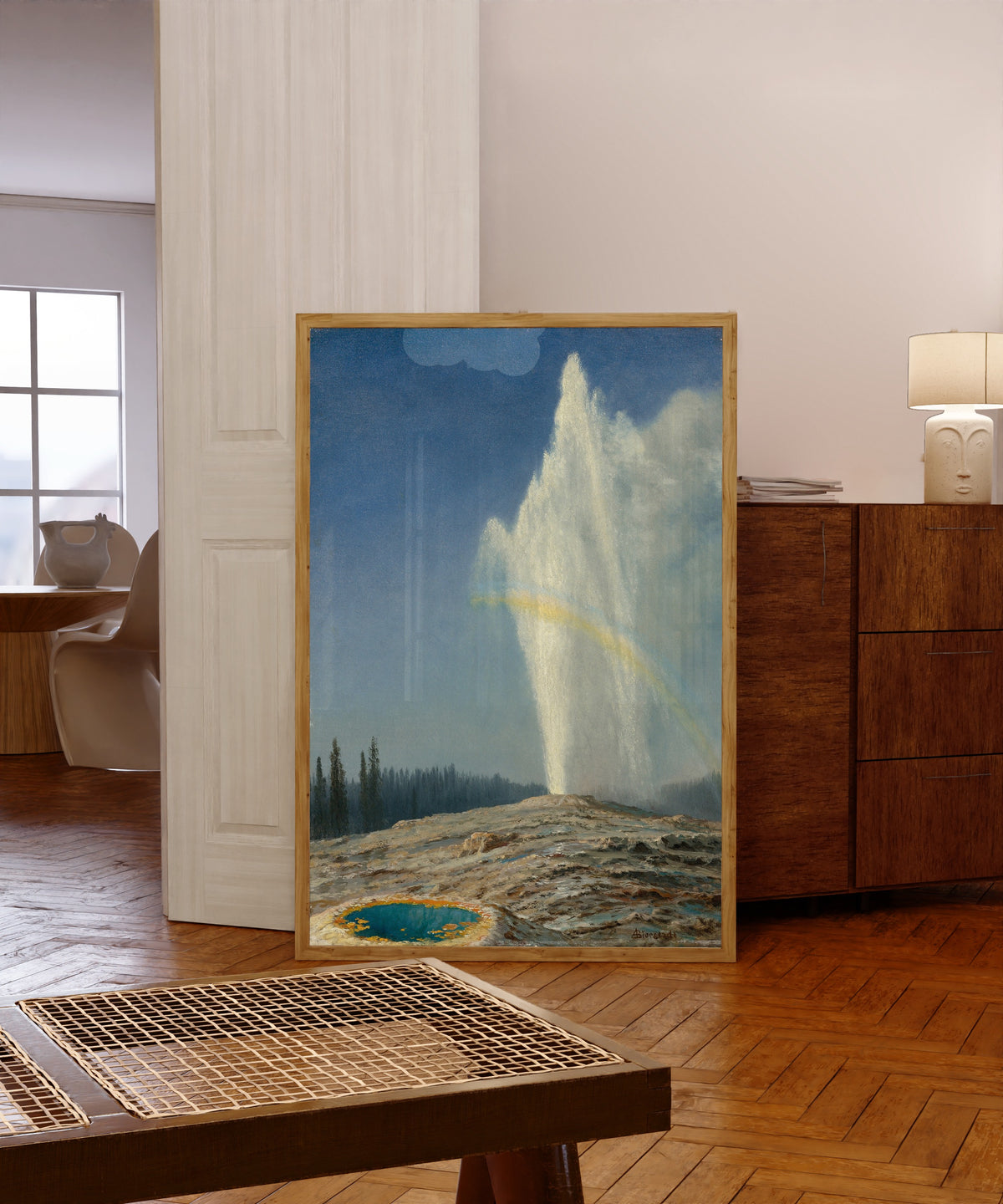 Framed art print of Old Faithful by Albert Bierstadt, in a light wood frame leaning in a warm room with a parquet floor