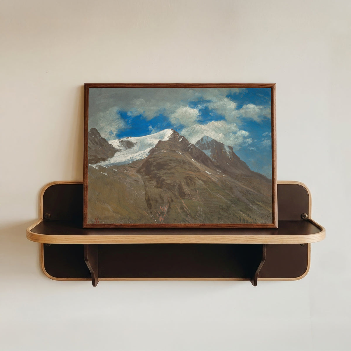 Framed art print of Peaks in the Rockies by Albert Bierstadt, in a dark wood frame resting on a wall shelf