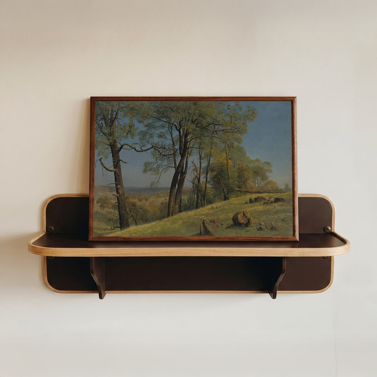 Framed art print of Rockland County, California by Albert Bierstadt, in a dark wood frame resting on a wall shelf