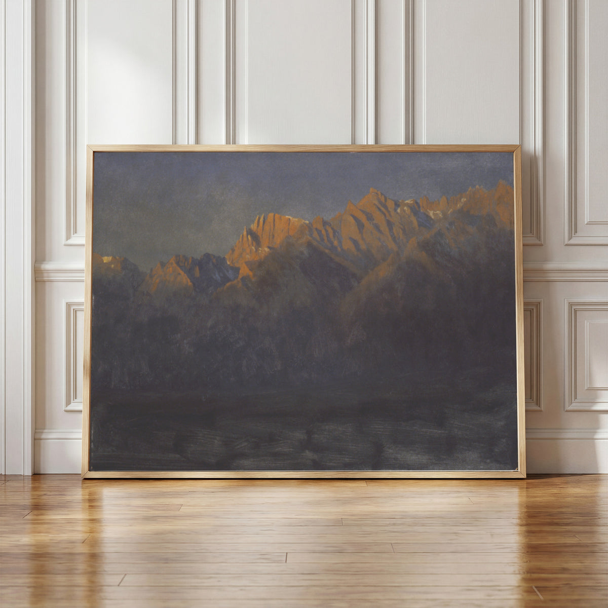 Framed art print of Sunrise in the Sierras by Albert Bierstadt, in a light wood frame leaning against a panelled white wall