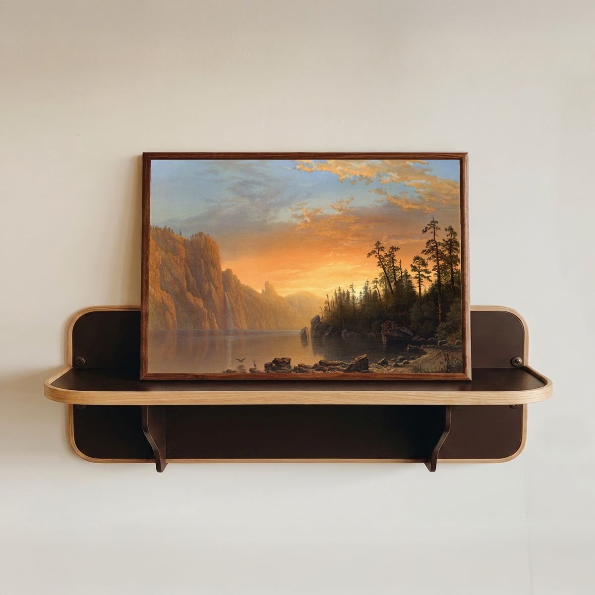 Framed art print of Sunset in California by Albert Bierstadt, in a dark wood frame resting on a wall shelf