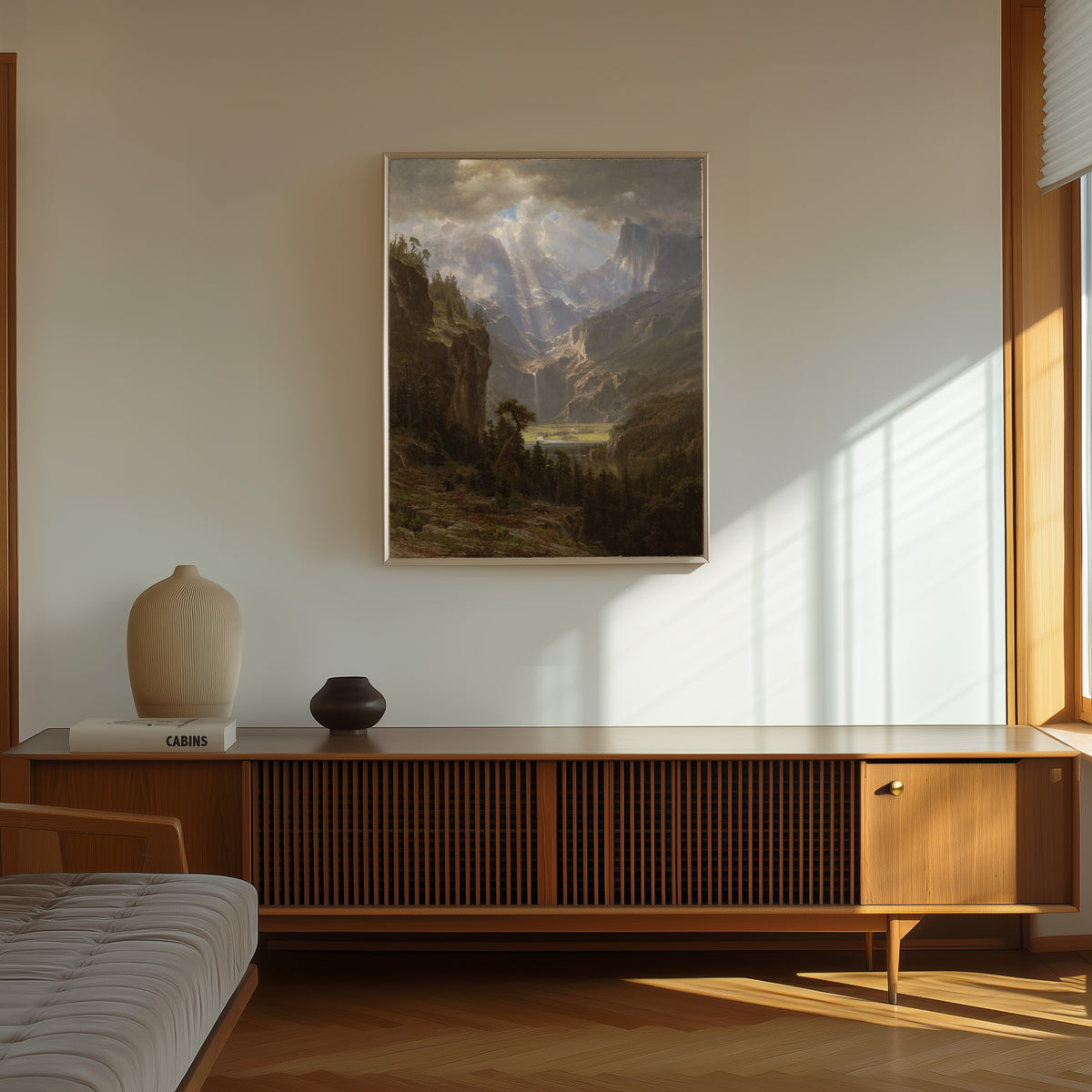 Framed art print of The Rocky Mountains, Lander's Peak (Alternate Version) by Albert Bierstadt, in a thin light frame on a sunlit wall above a wooden sideboard