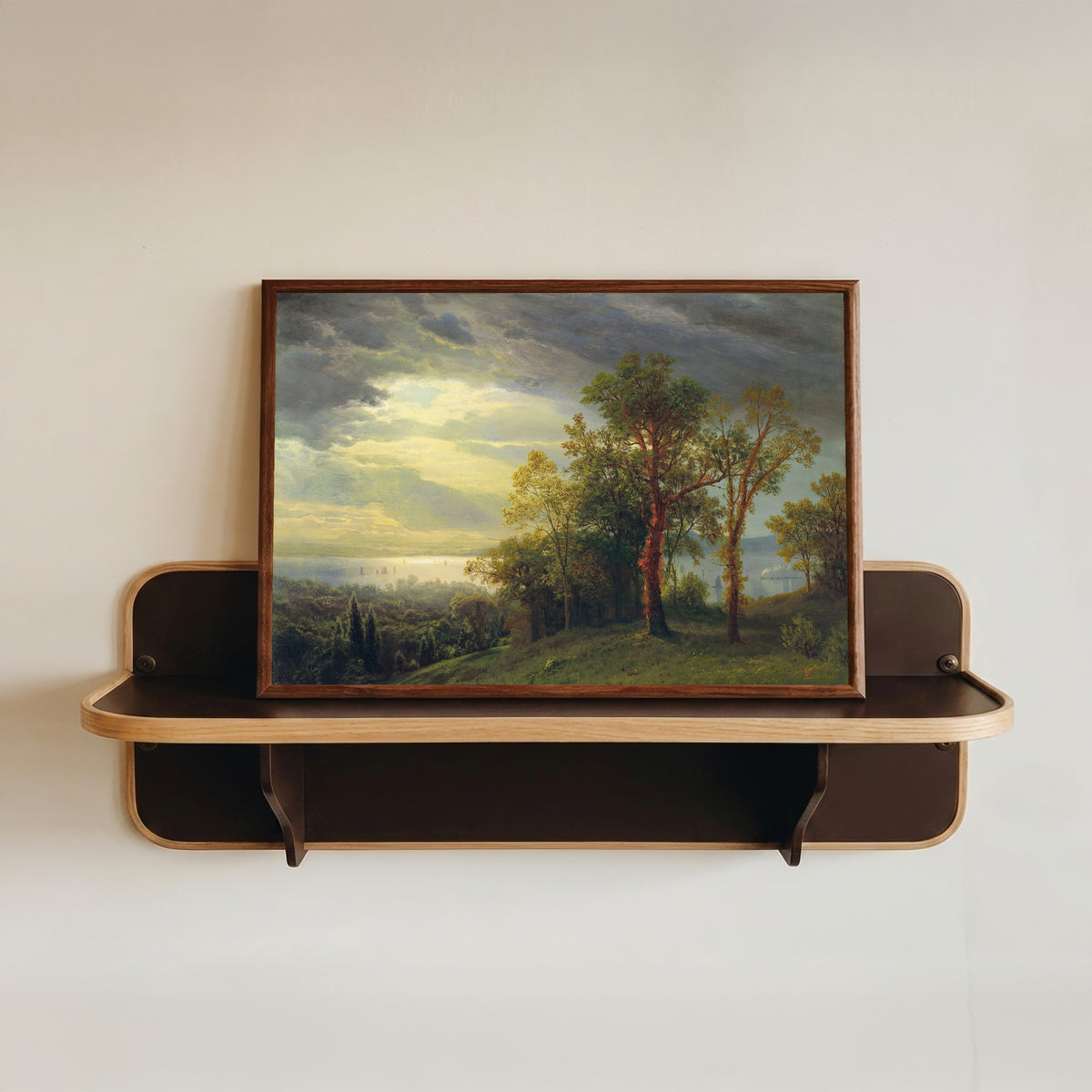 Framed art print of View on the Hudson by Albert Bierstadt, in a dark wood frame resting on a wall shelf