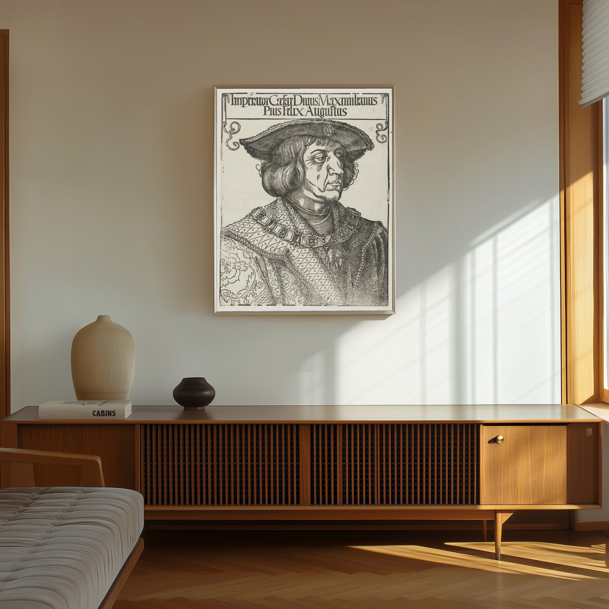 Framed art print of Emperor Maximilian I by Albrecht Dürer, in a thin light frame on a sunlit wall above a wooden sideboard