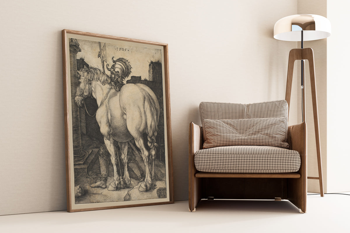 Framed art print of The Great Horse by Albrecht Dürer, leaning against a wall beside an armchair and a floor lamp