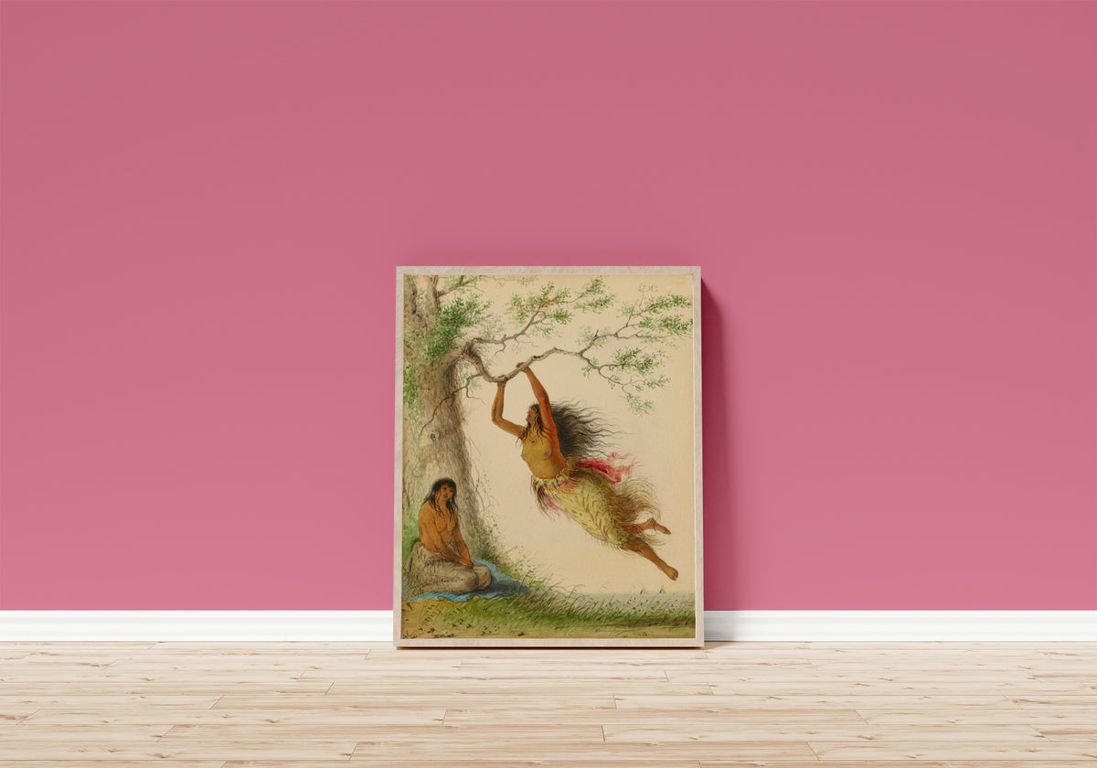 Framed art print of Indian Girls Swinging by Alfred Jacob Miller, in a light wood frame leaning on a pink wall above a wooden floor