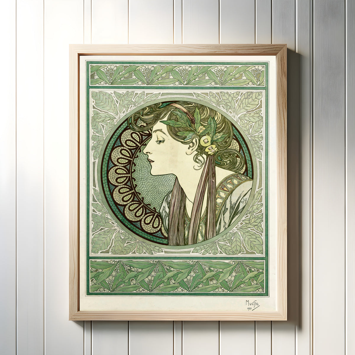 Framed art print of Laurel by Alphonse Mucha, in a light wood frame on a white panelled wall