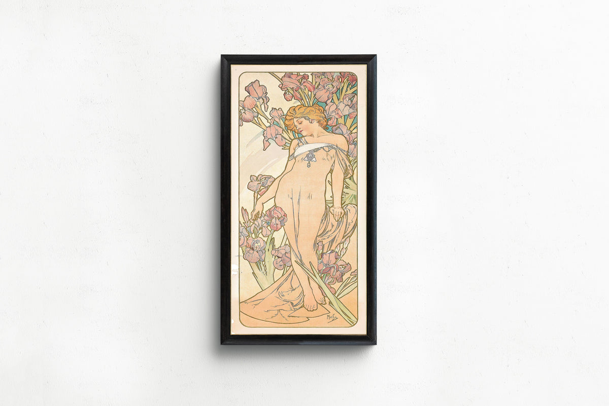 The Iris by Alphonse Mucha — in a slim black frame on a plain white wall