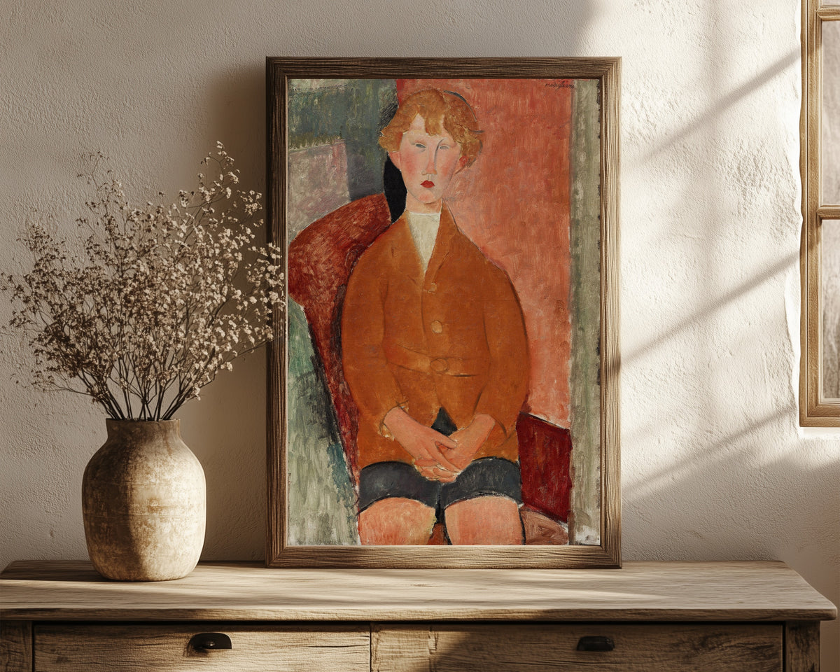 Framed art print of Boy in Short Pants by Amedeo Modigliani, in a dark wood frame leaning on a rustic console beside dried flowers