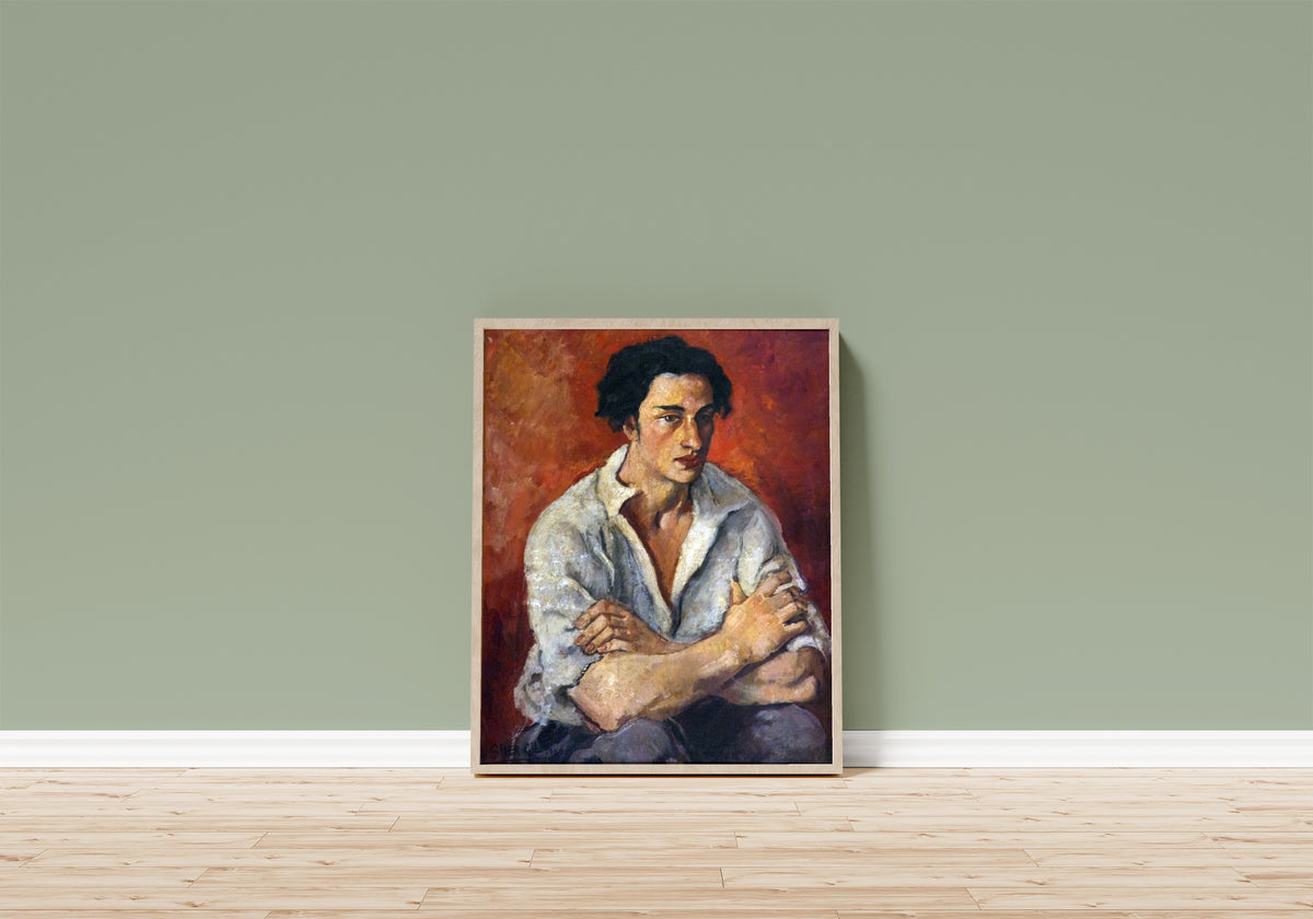 Framed art print of Portrait of a Young Man (1930) by Amrita Sher-Gil, in a light wood frame leaning on a sage green wall above a wooden floor