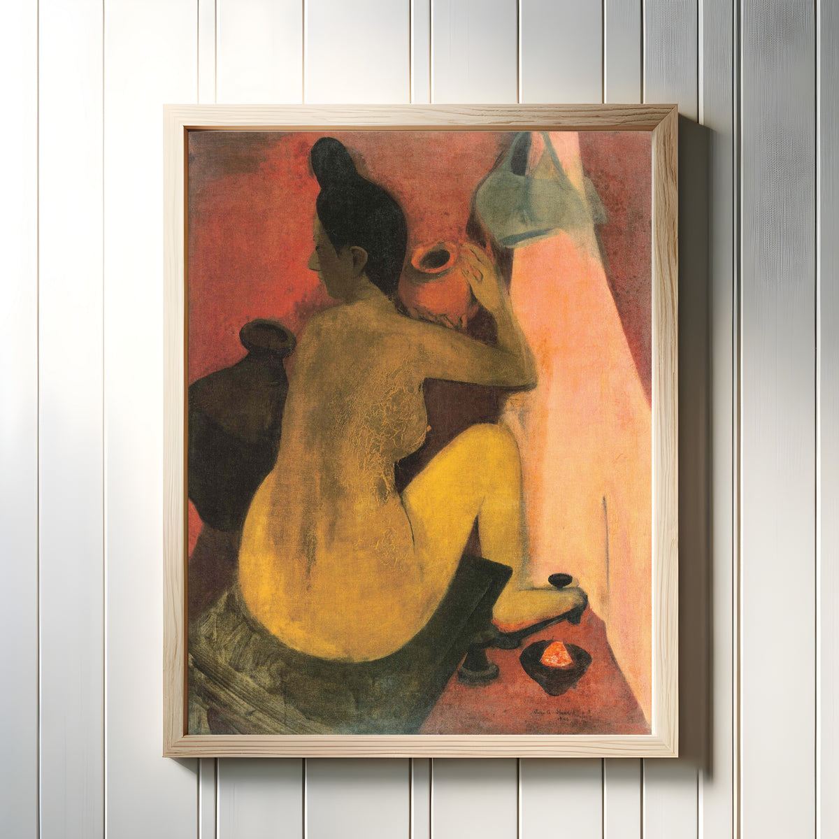 Framed art print of Woman at Bath (1940) by Amrita Sher-Gil, in a light wood frame on a white panelled wall