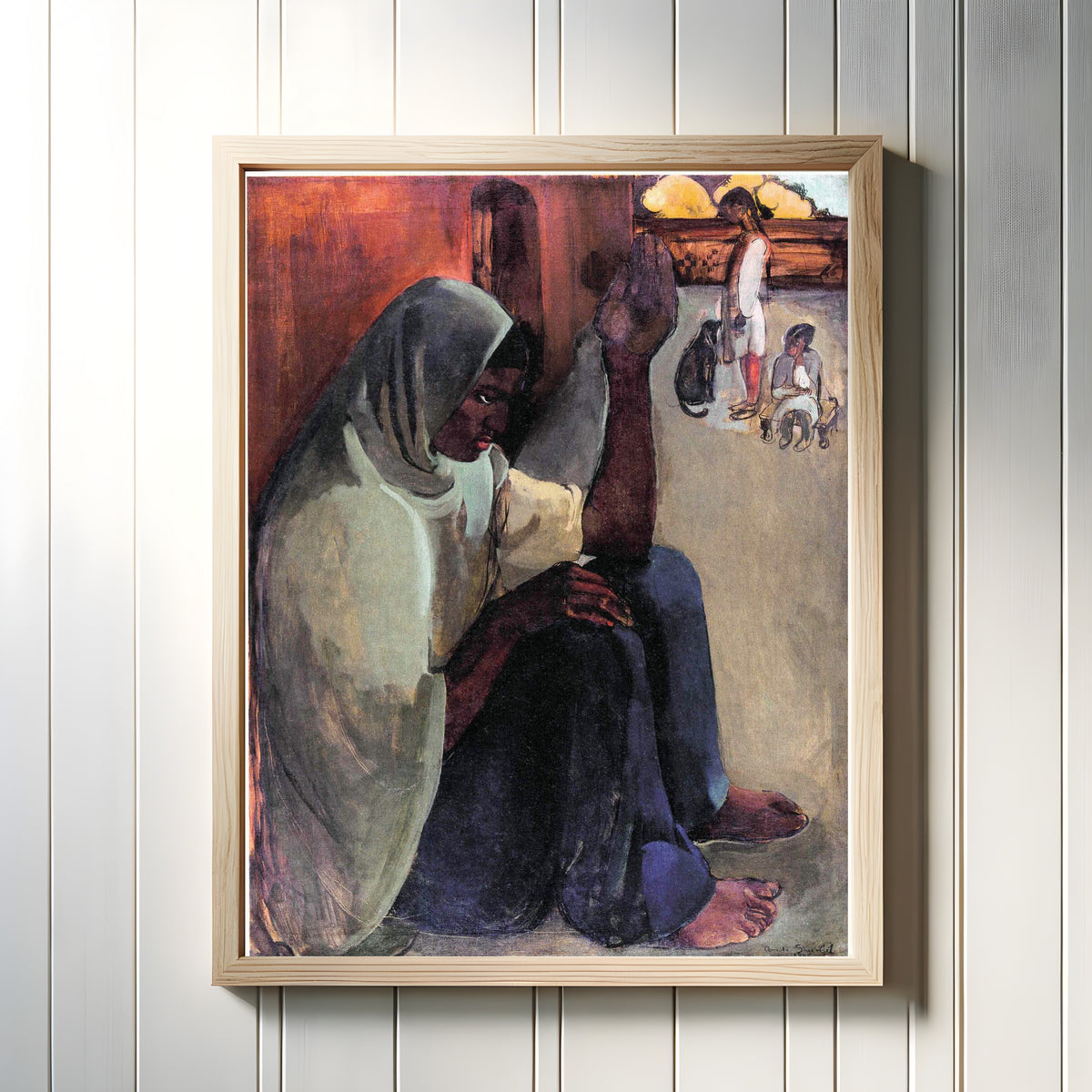 Framed art print of Woman on Terrace (1935) by Amrita Sher-Gil, in a light wood frame on a white panelled wall
